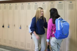 High School students at lockers carrying backpacks